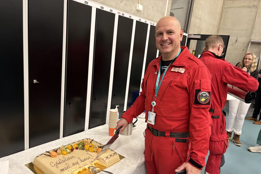 Mann i rød luftambulanseuniform foran en stor kake