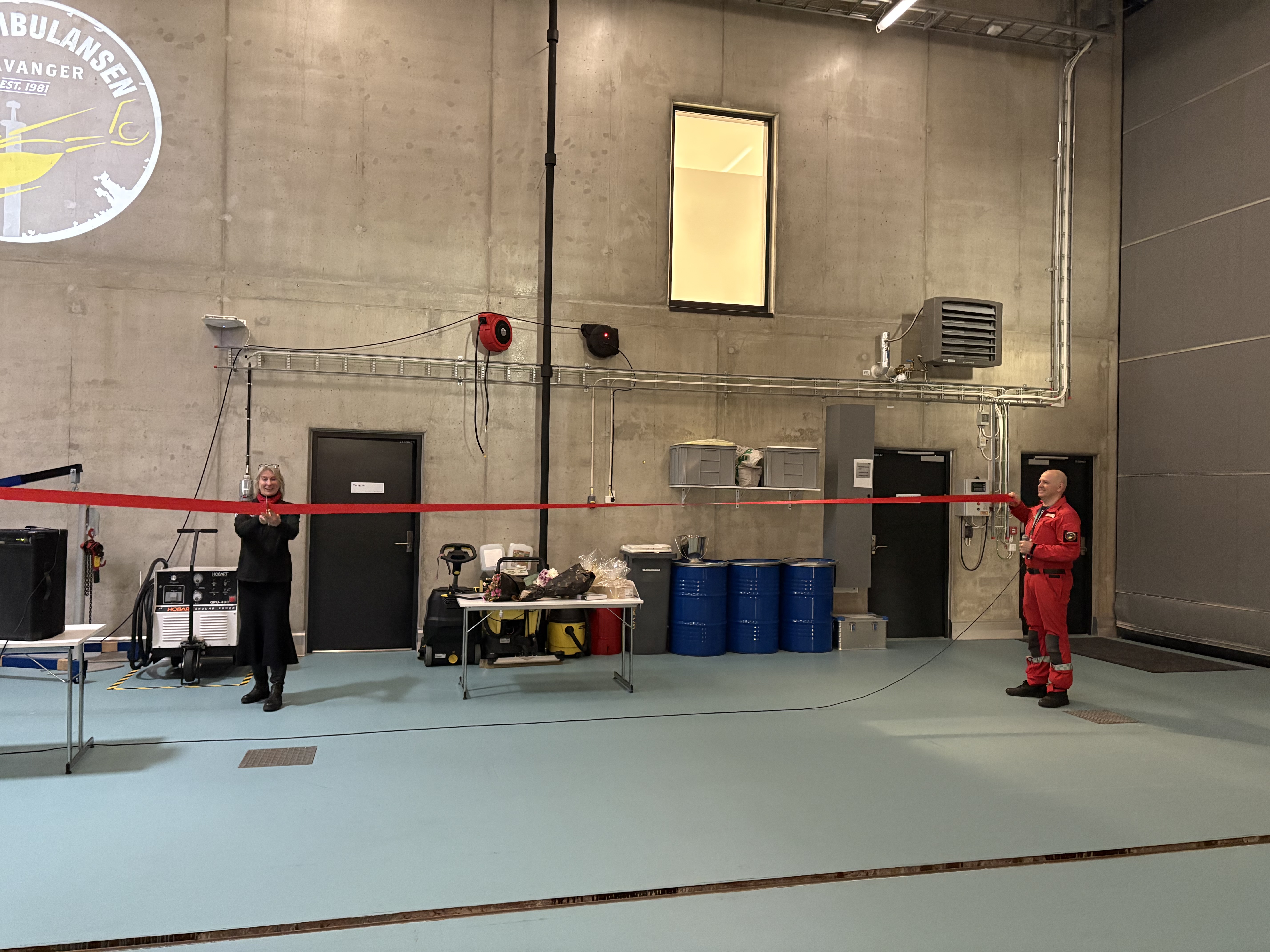 En dame klipper over en rød snor som en mann holder