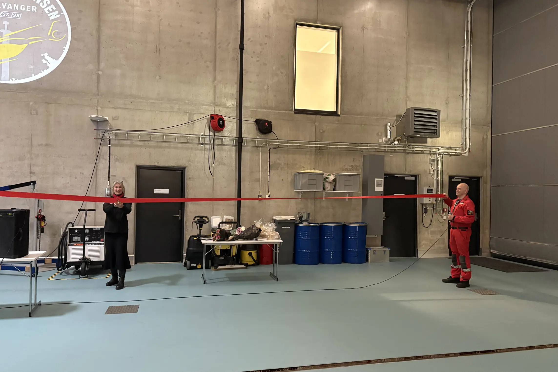 En dame klipper over en rød snor som en mann holder