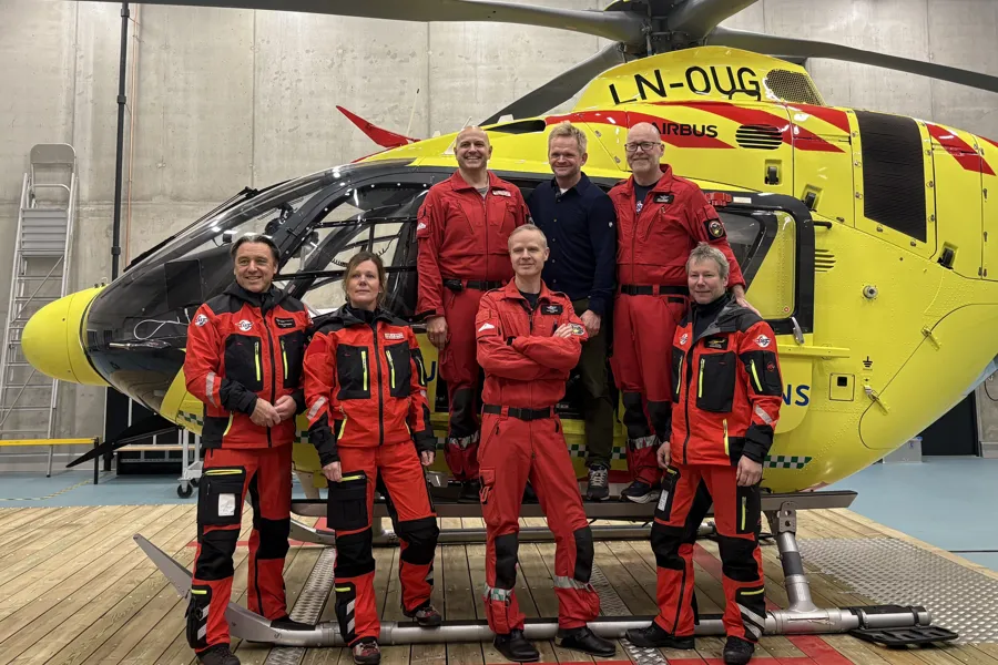 En gruppe menn i oransje dresser står foran en gul og svart romferge