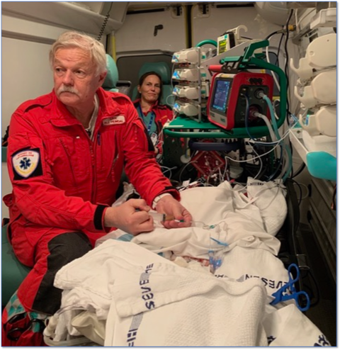 En mann i rød frakk og en kvinne i en sykehusseng