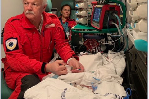 En mann i rød frakk og en kvinne i en sykehusseng