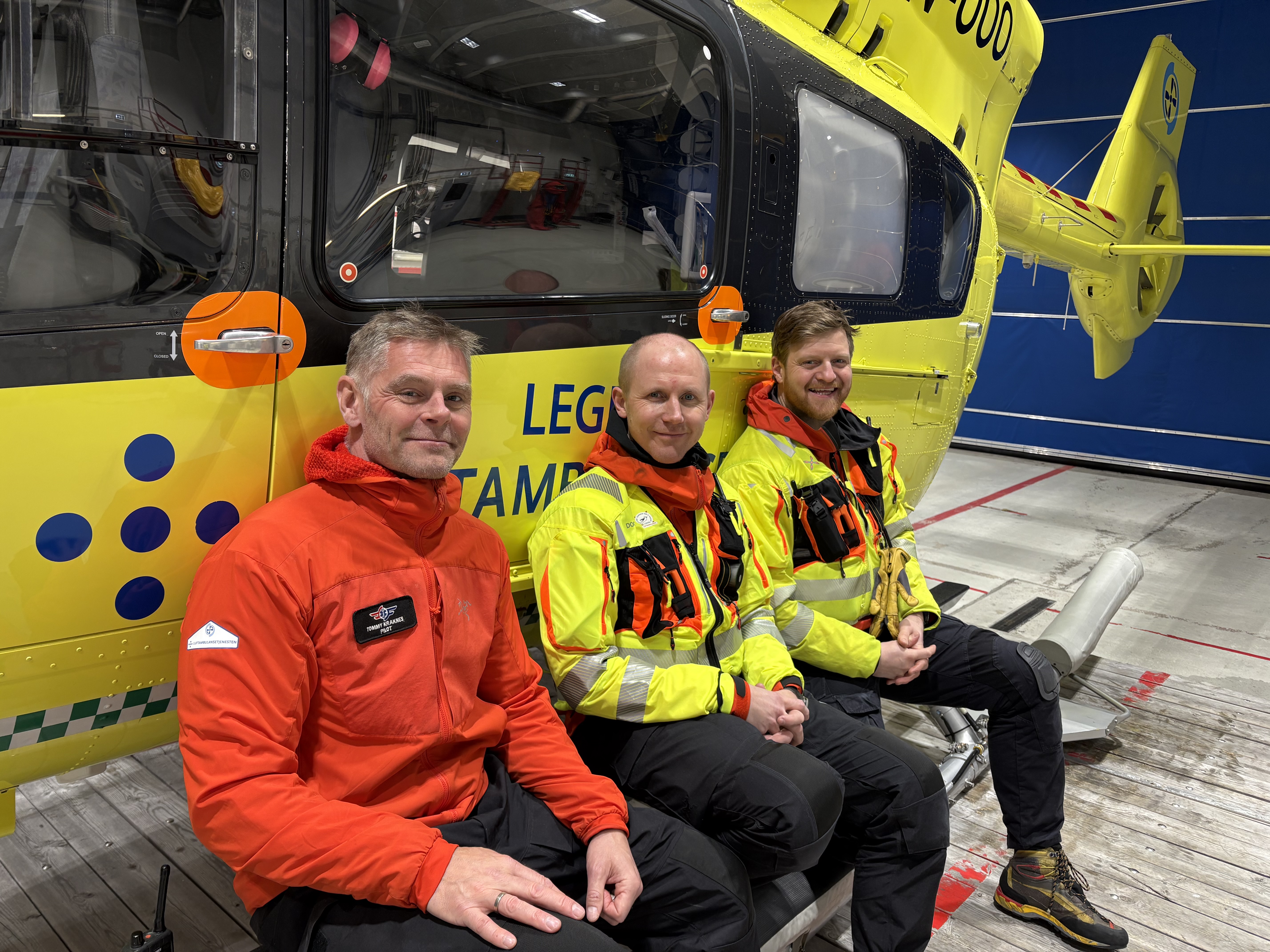 Tre menn i uniform foran et ambulansehelikopter