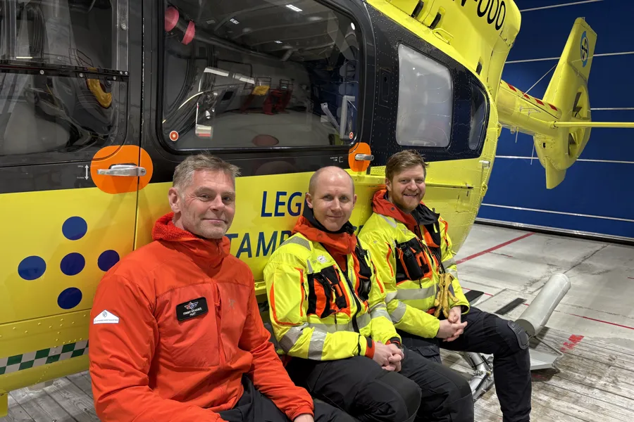 Tre menn i uniform foran et ambulansehelikopter
