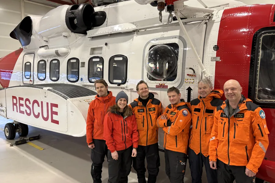 Fem menn og en kvinne i uniform foran et redningshelikopter