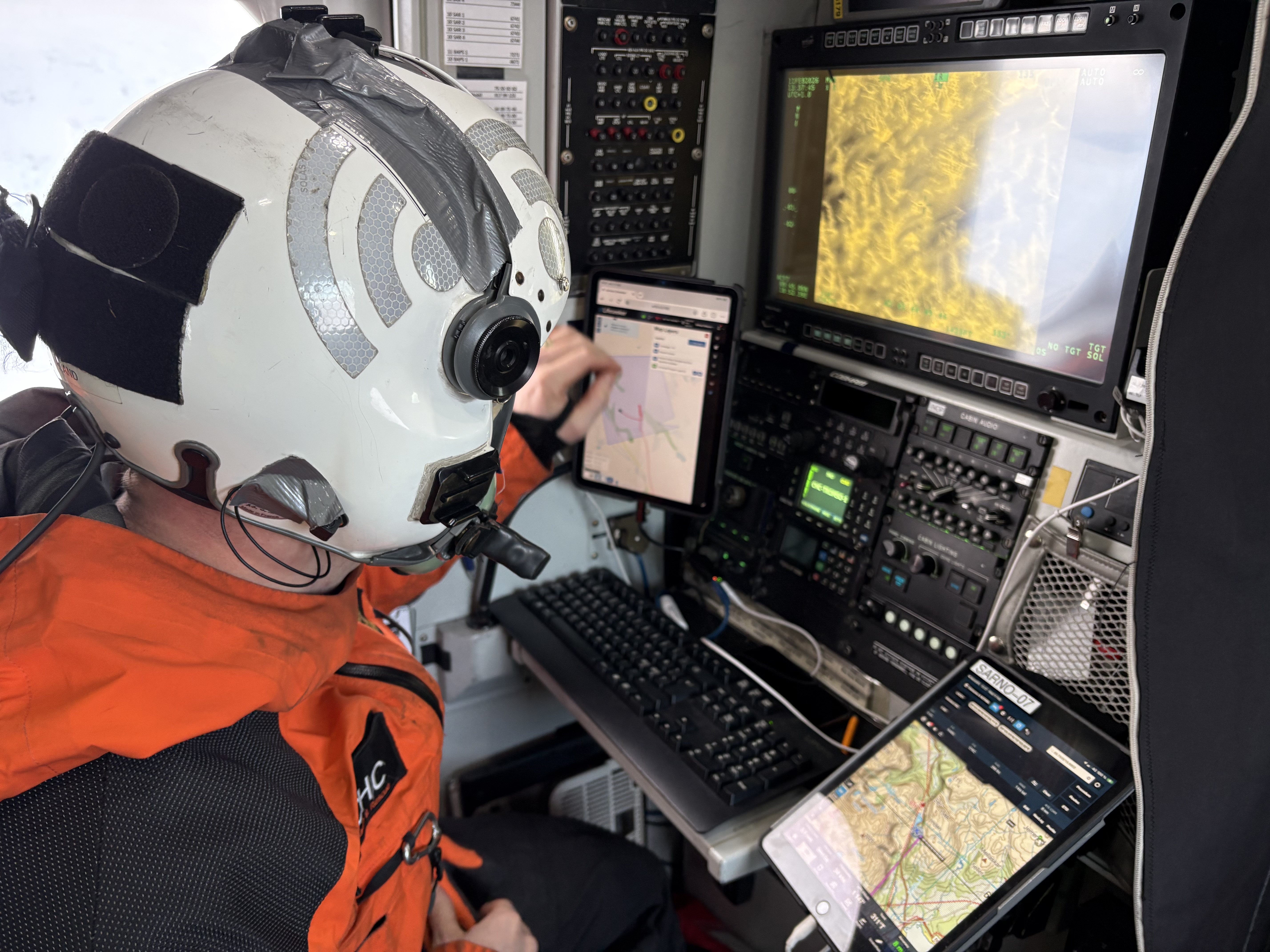 Mann med hjelm foran datamaskiner inne i et helikopter