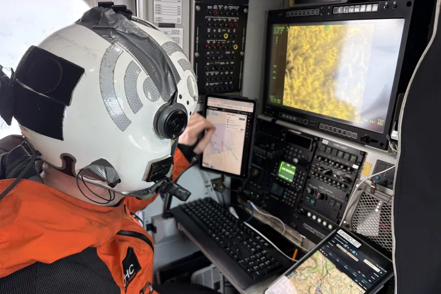 Mann med hjelm foran datamaskiner inne i et helikopter