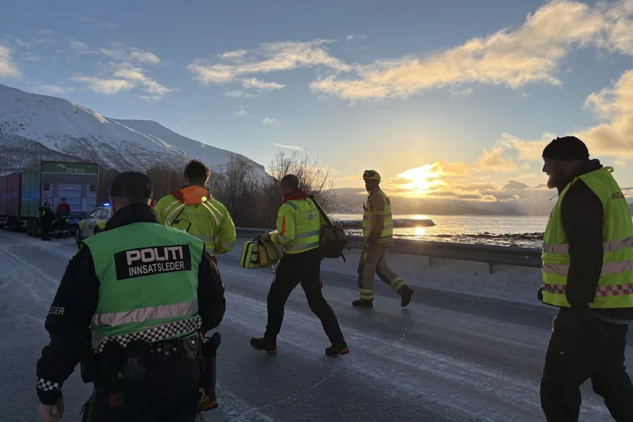 Brann, politi og ambulansepersonell som går på en vei med snø og fjell i bakgrunnen