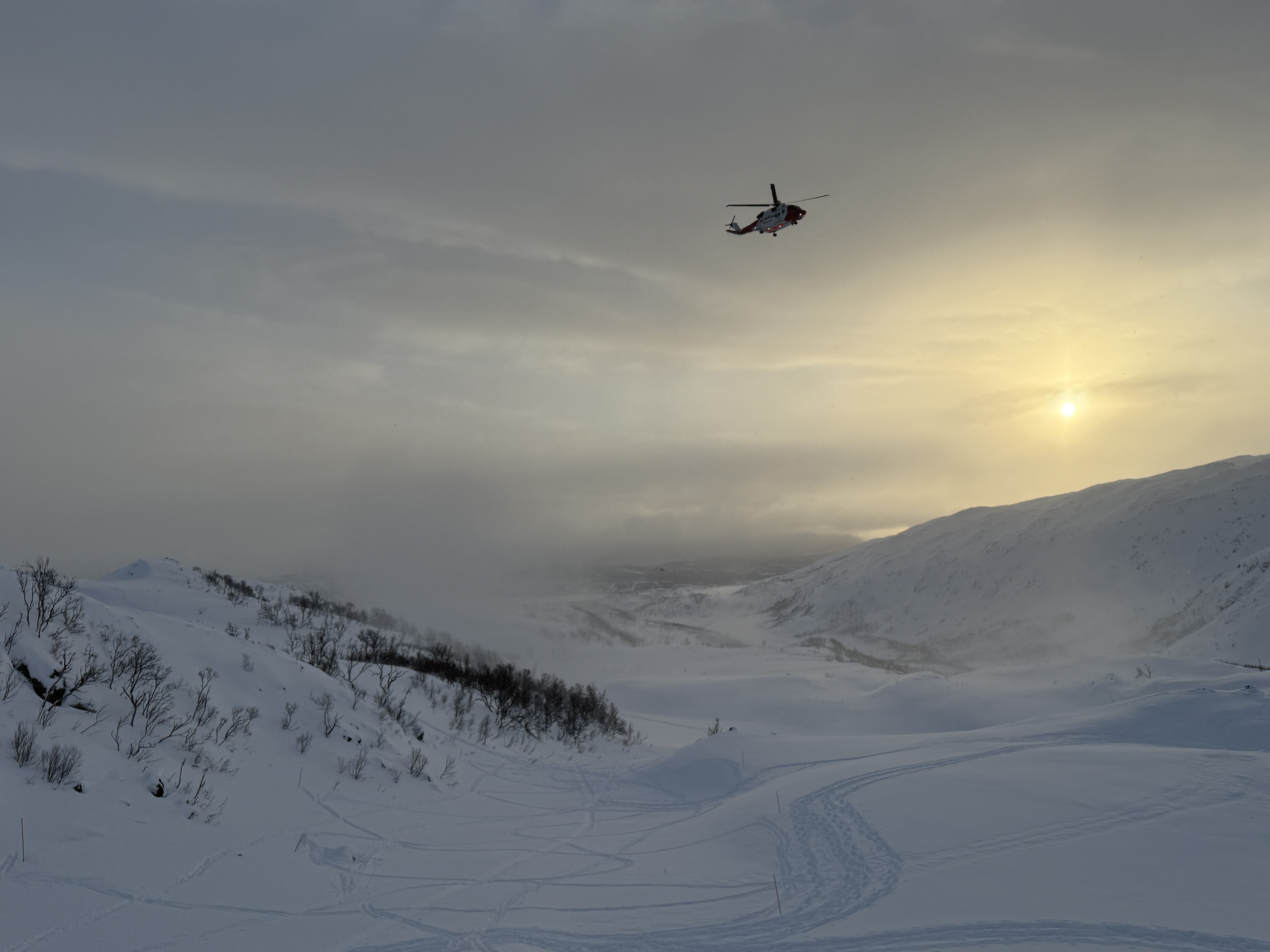 Et helikopter som flyr over et snødekt fjell