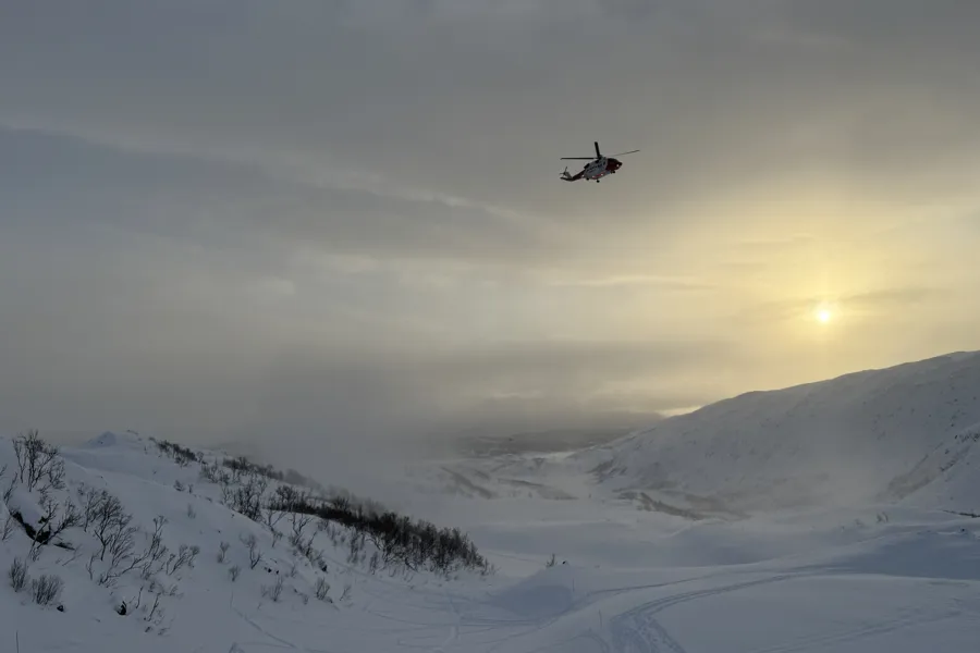 Et helikopter som flyr over et snødekt fjell
