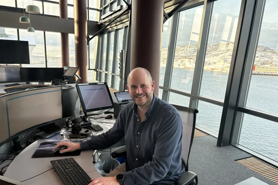 En smilende mann i en operatsjonssentral