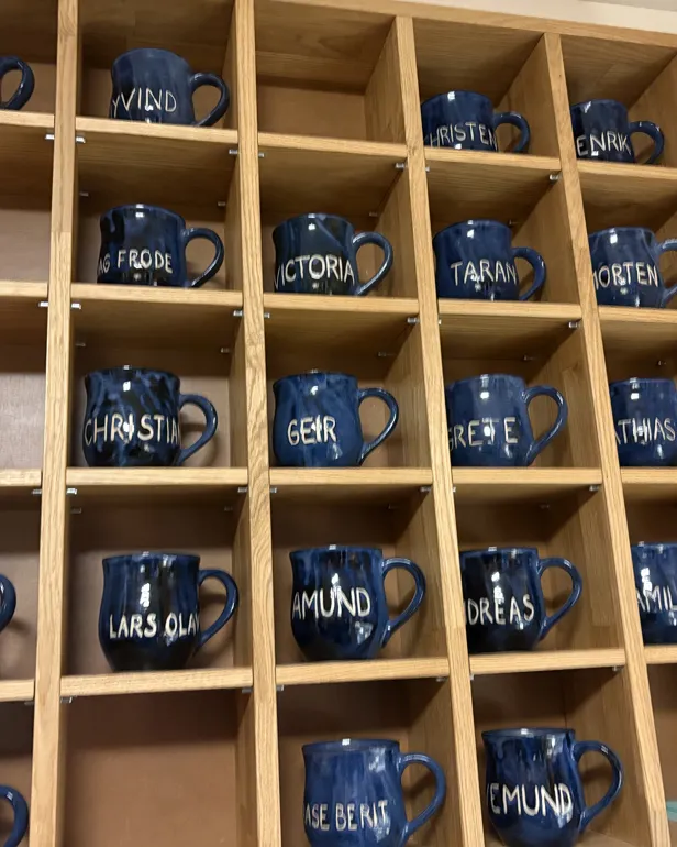 Hyller med blå kopper med navn på