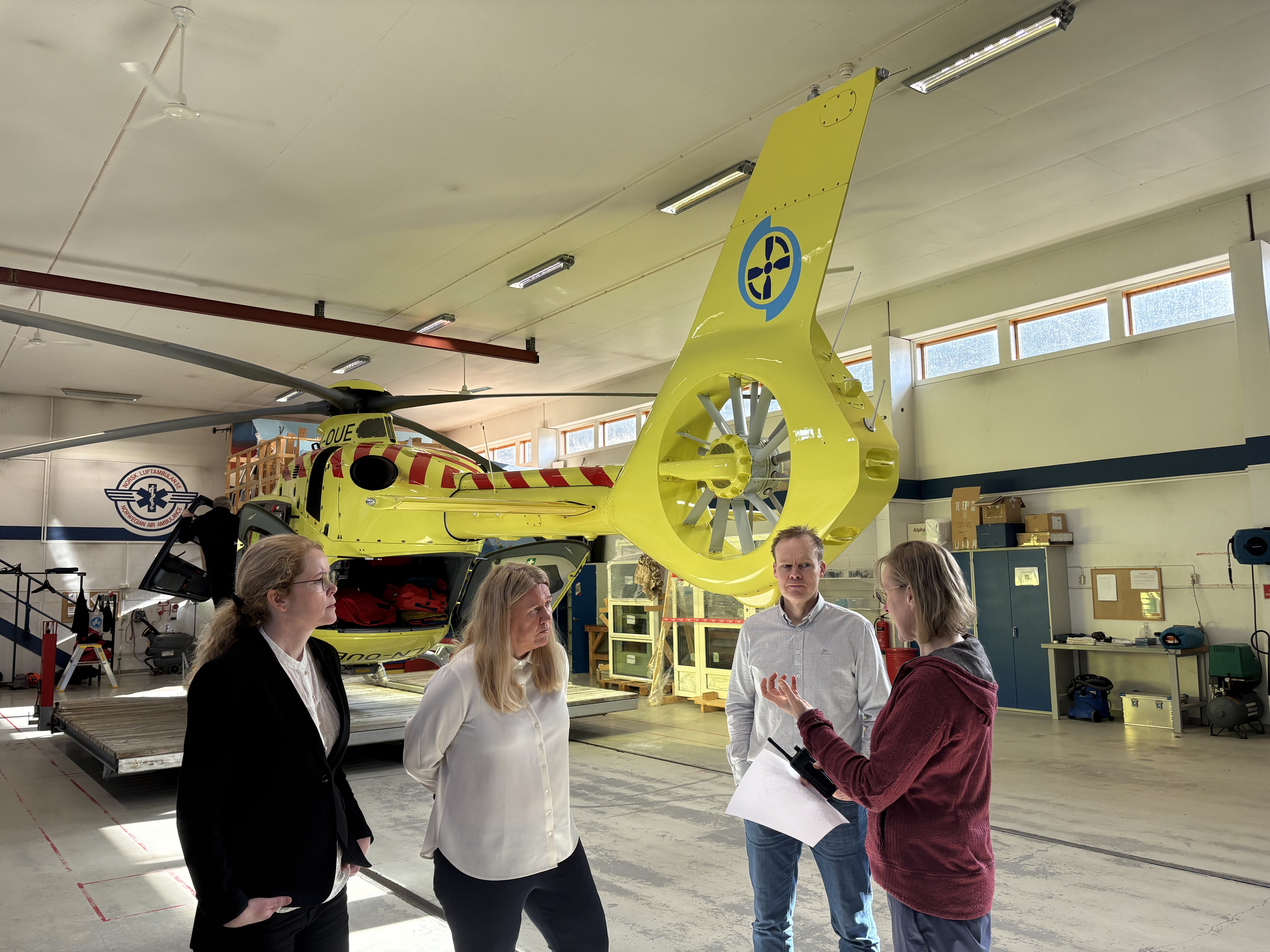 Tre kvinner og en mann foran et helikopter