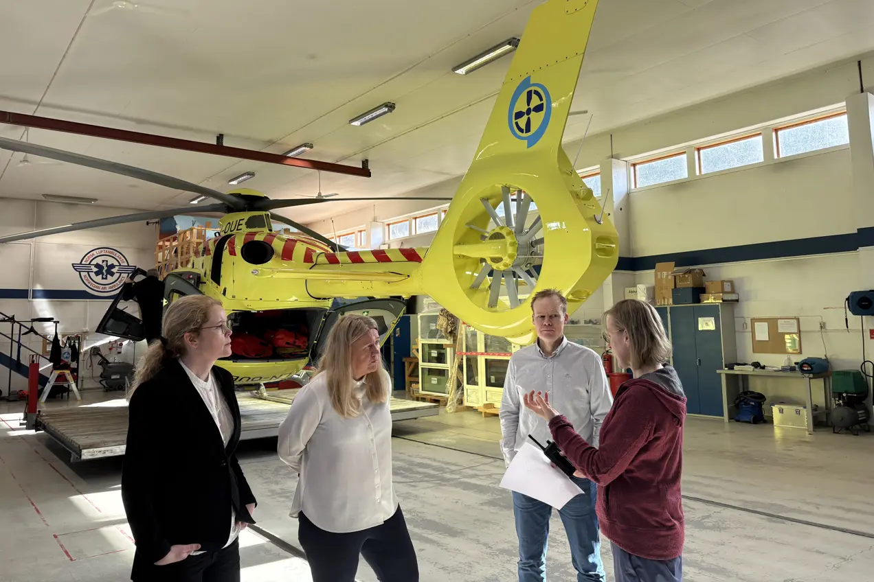 Tre kvinner og en mann foran et helikopter