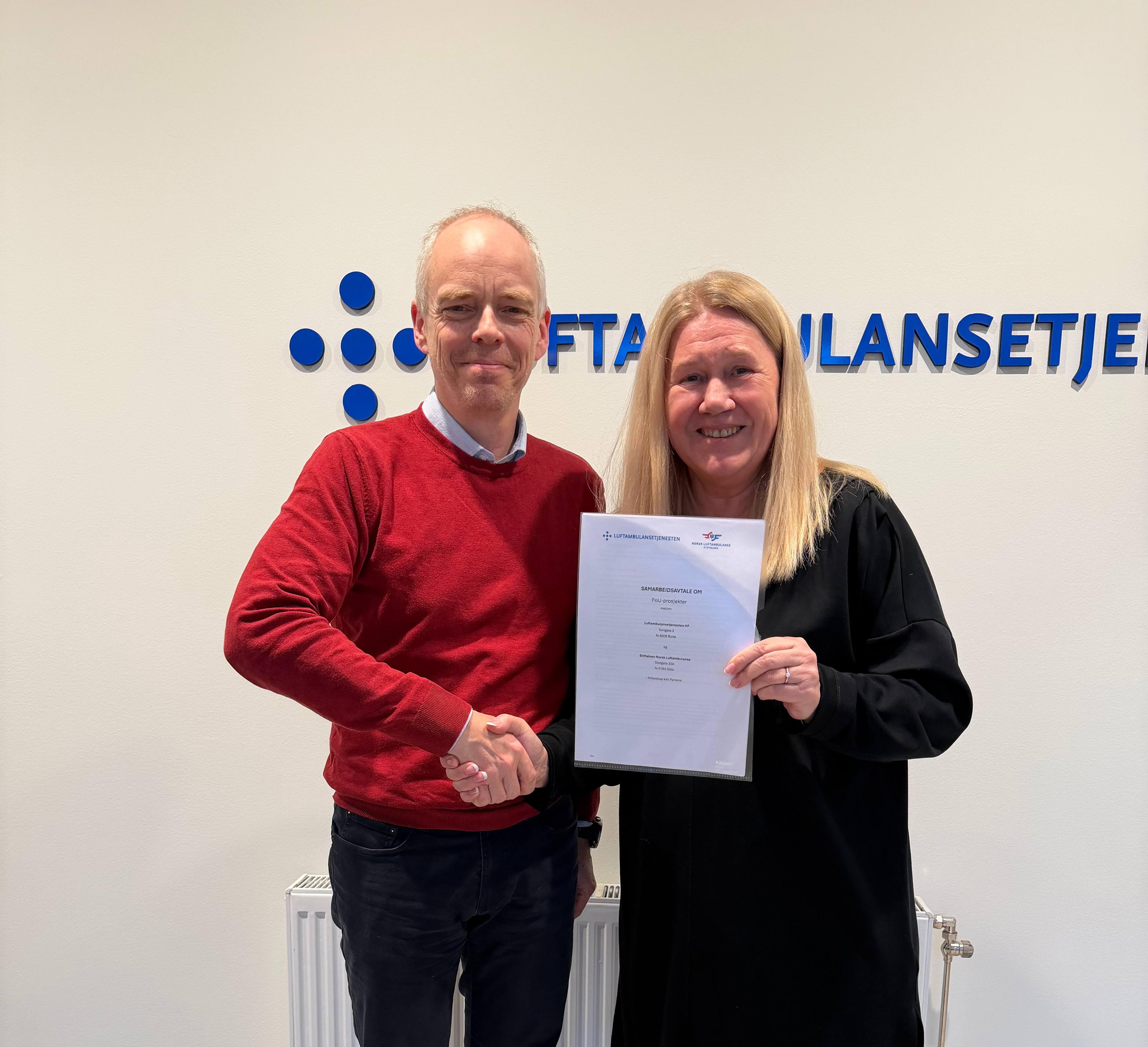 En smilende mann og med håndtrykk og avtale