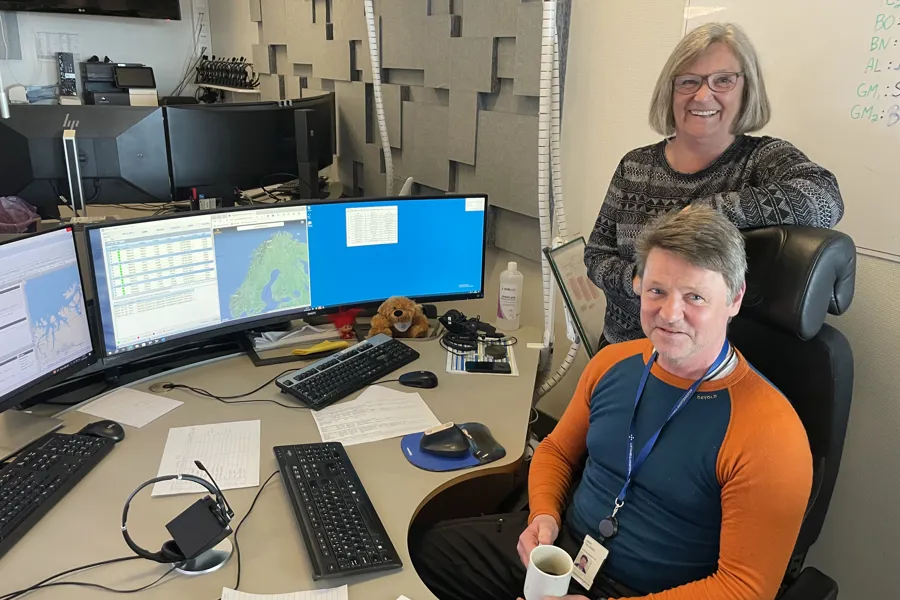 En mann og en kvinne som sitter ved et skrivebord med datamaskiner