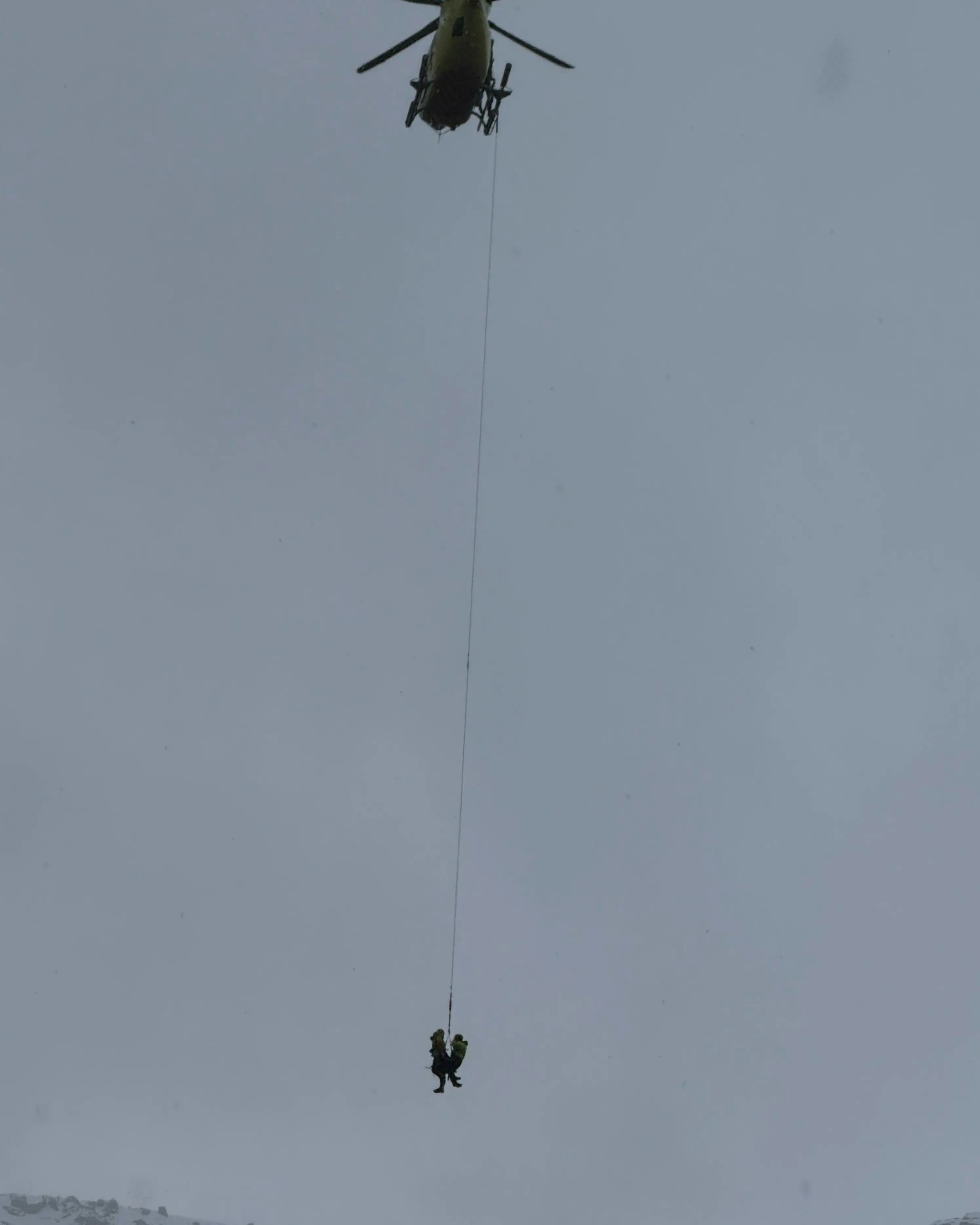 Et helikopter som flyr med personer hengende i tau