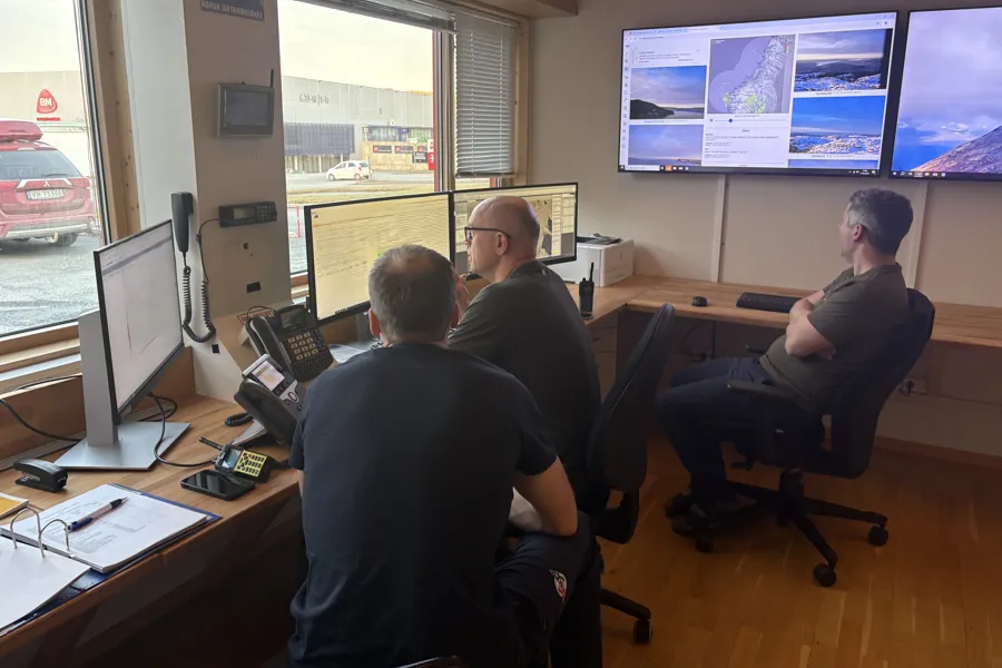 Menn som sitter ved et skrivebord med datamaskiner