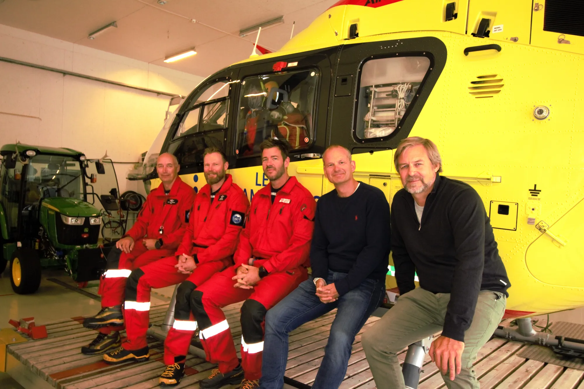 En gruppe menn i røde jumpsuits som sitter på et tog