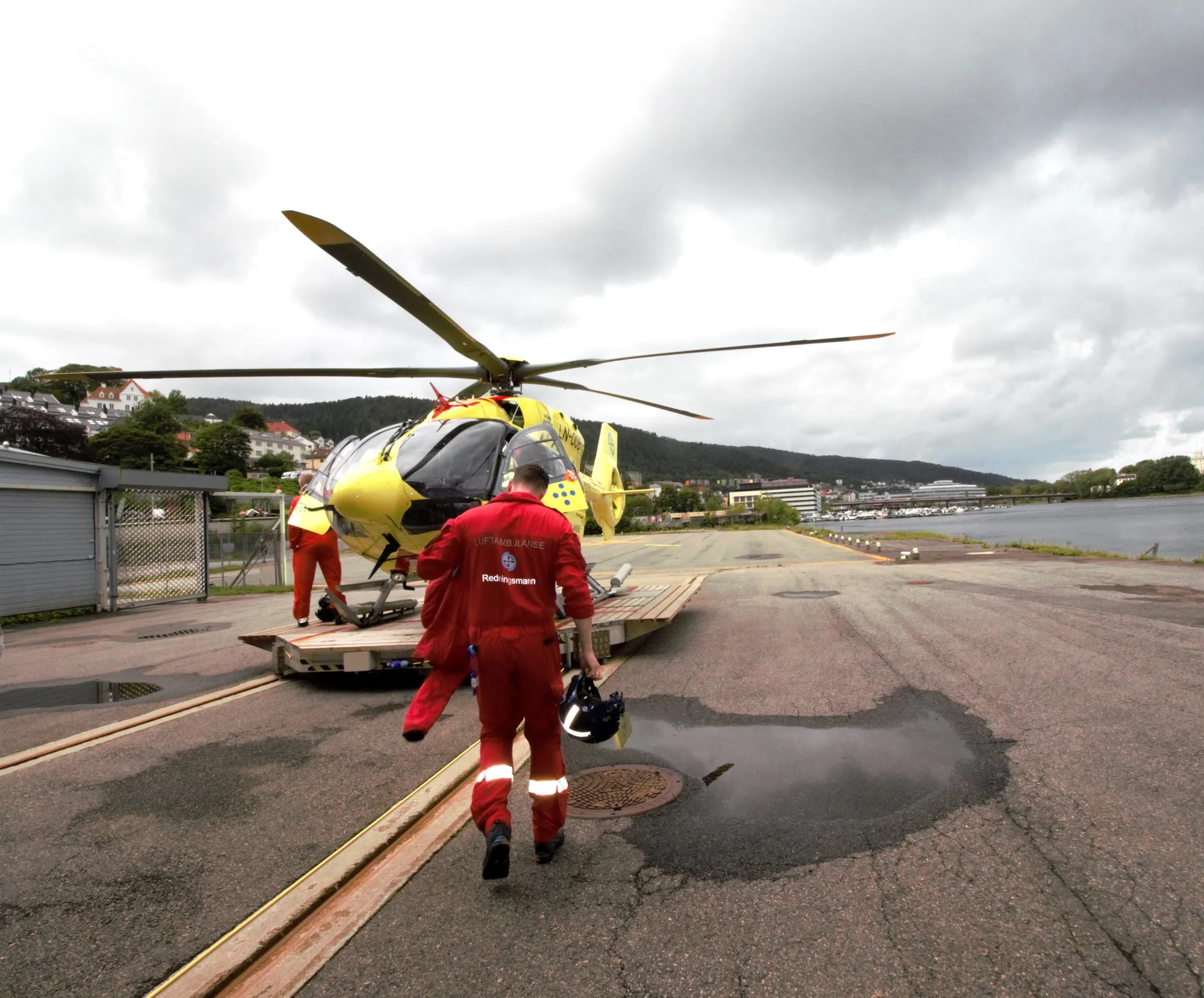 En person i rød jumpsuit ved et helikopter