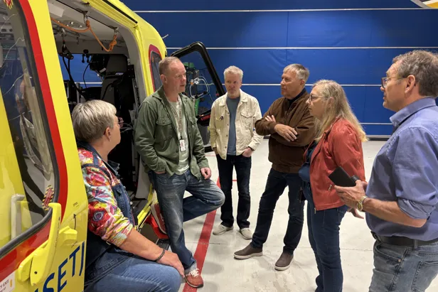 En snakker mann i åpningen på et ambulansehelikopter med tilhørere rundt