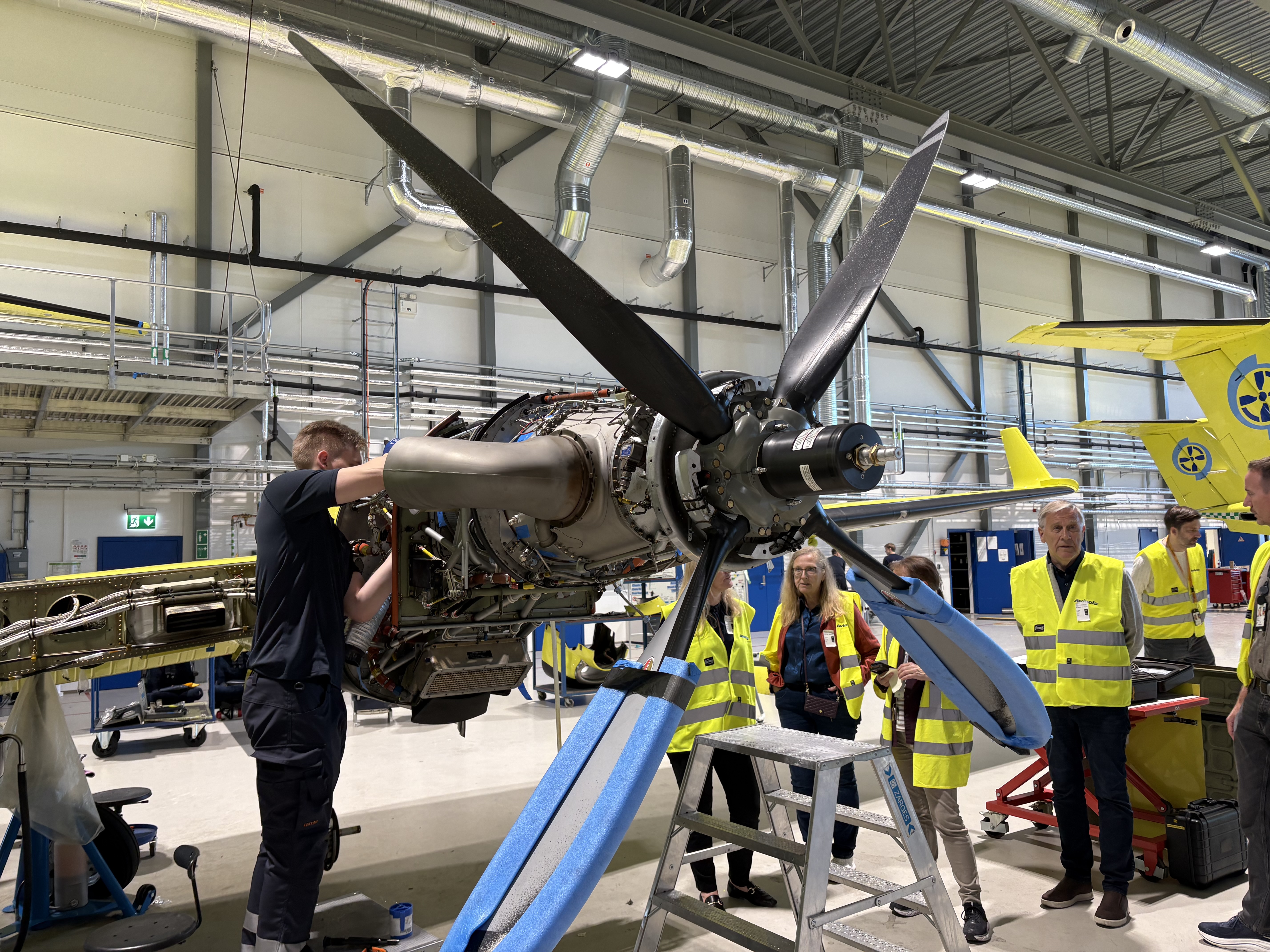 En mann skrur på en flypropell med tilhørere rundt