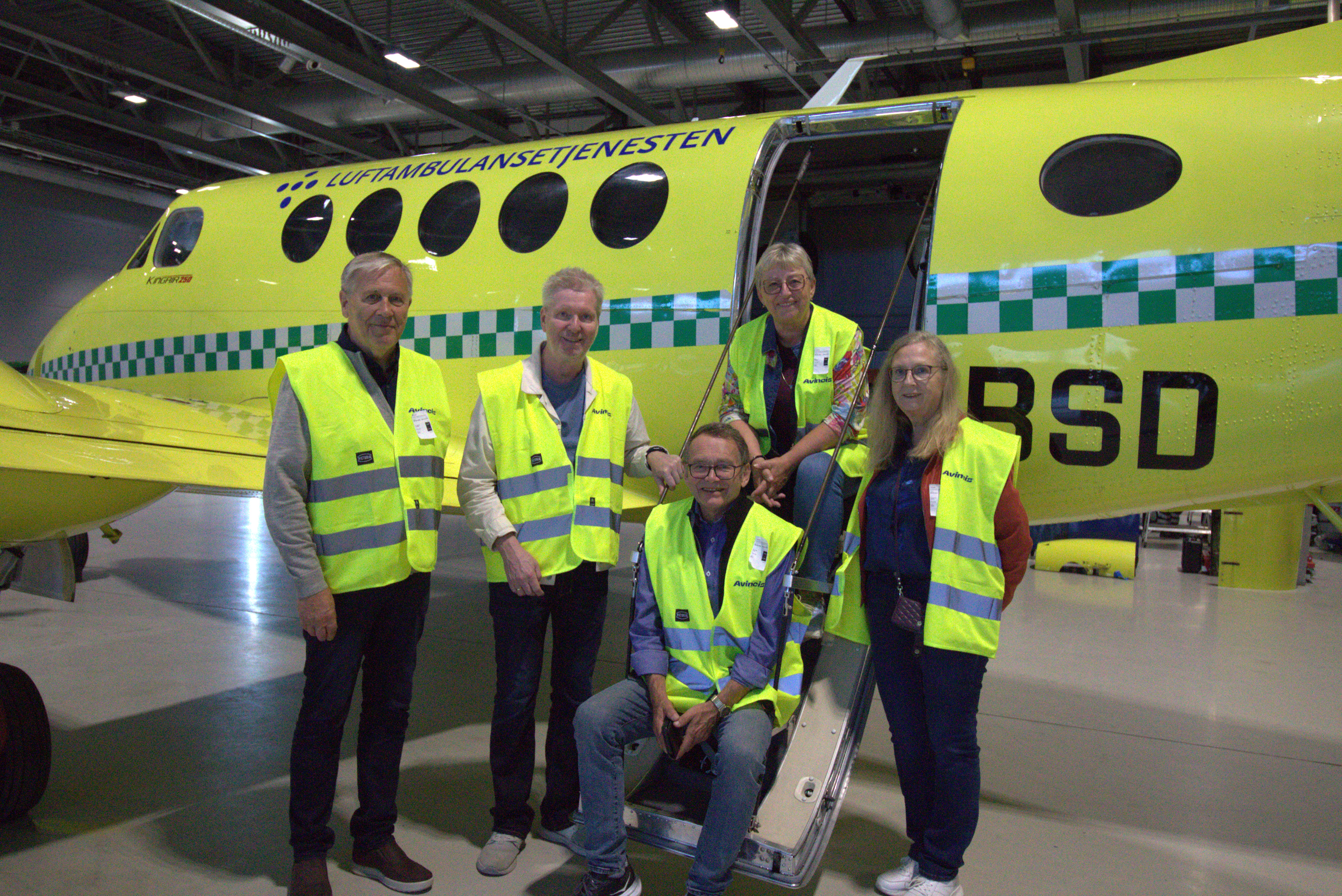 Kvinner og menn foran et ambulansefly