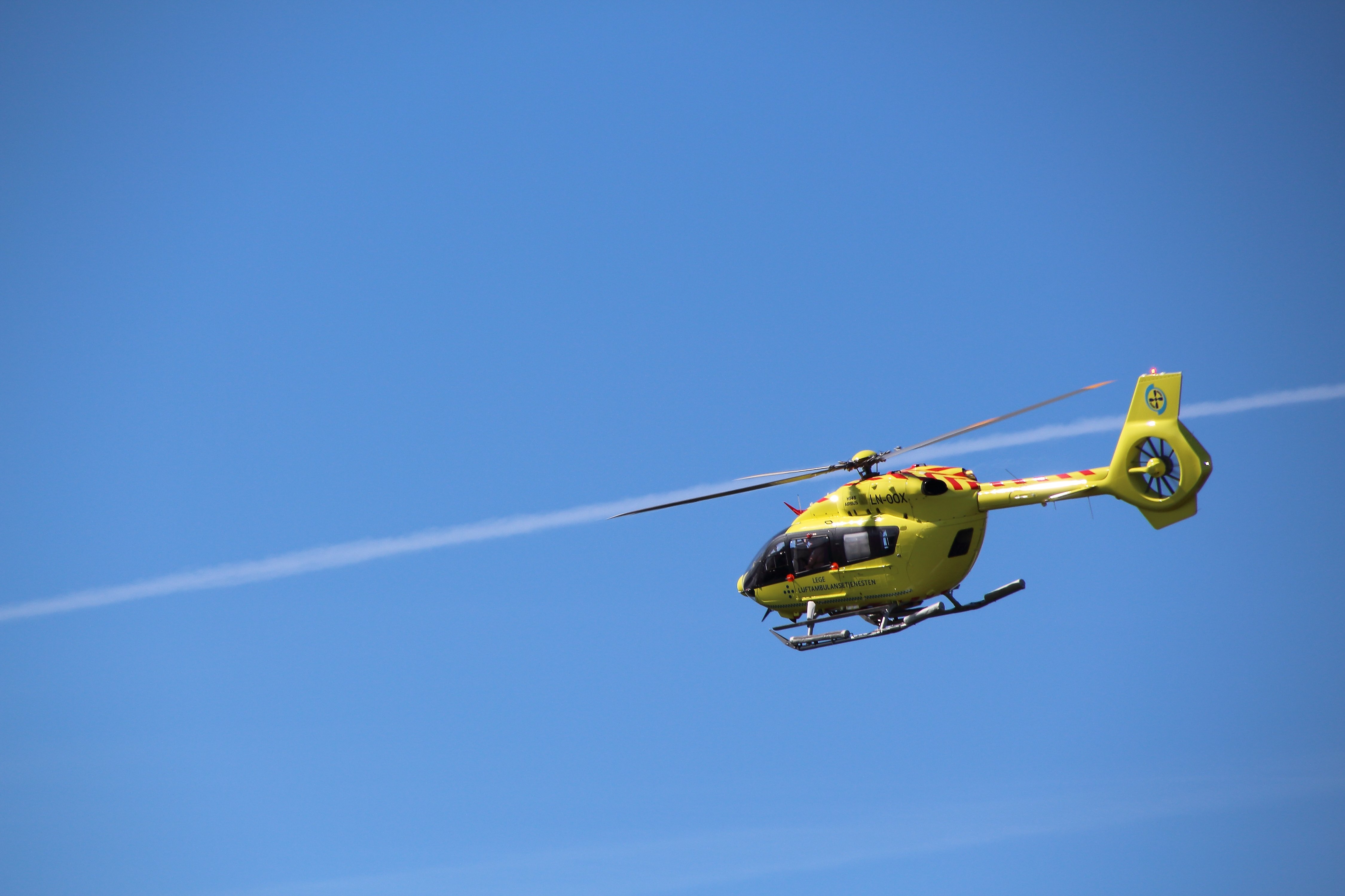 Et gult ambulansehelikopter mot blå himmel
