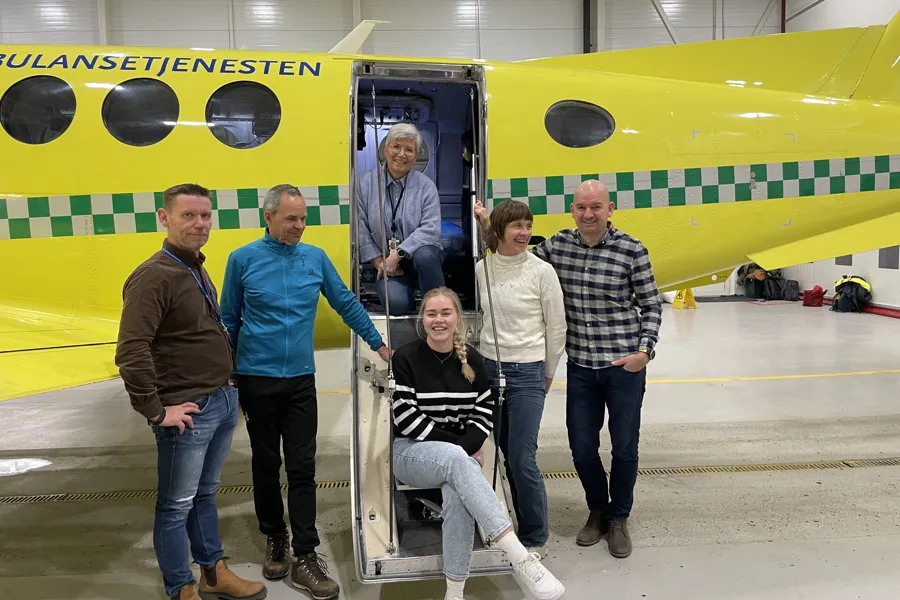 En gruppe mennesker som poserer for et bilde foran et gult fly