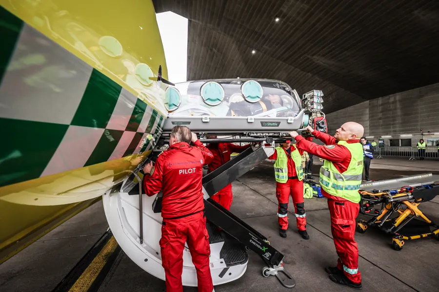 En smittebåre føres inn i et gult ambulansefly