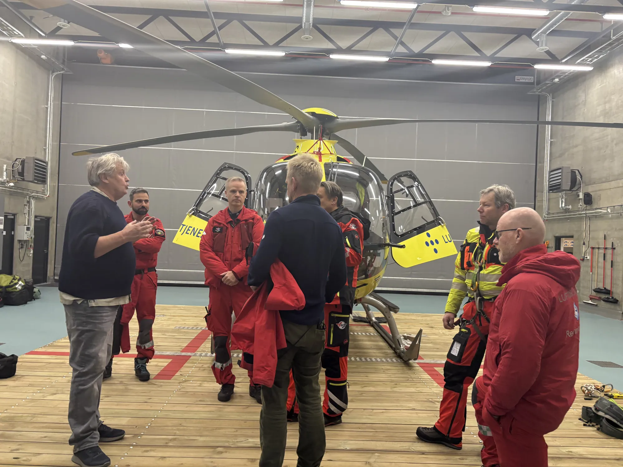 En gruppe mennesker som står rundt et gult helikopter