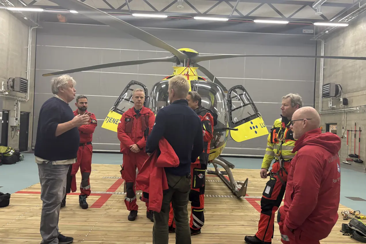 En gruppe mennesker som står rundt et gult helikopter